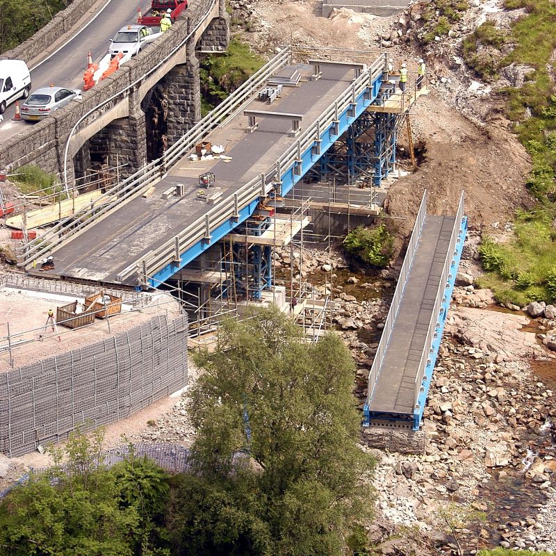 MH International vehicle beam bridge flat top next to bridge over river