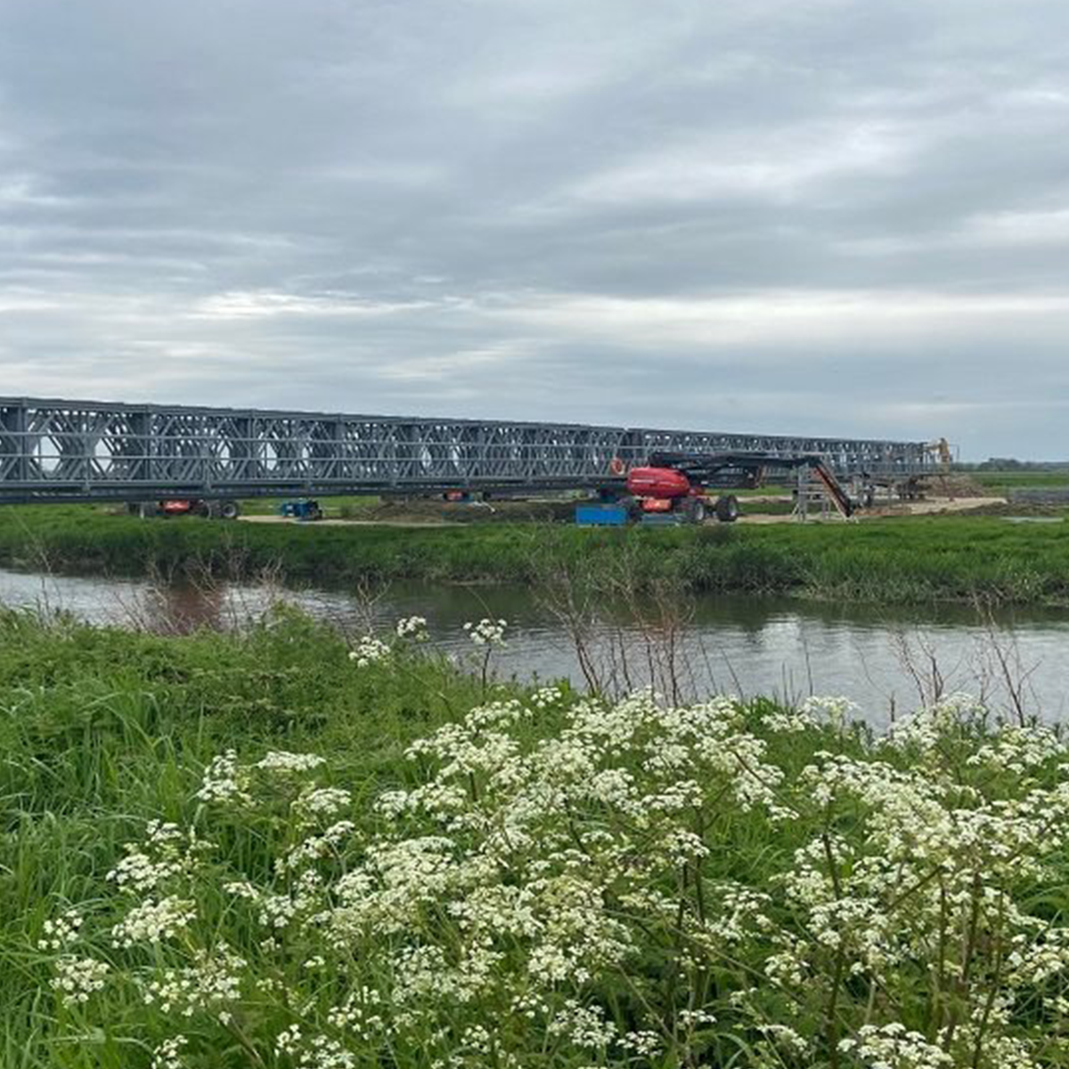 MH International compact 200 panel bridge over water next to fields
